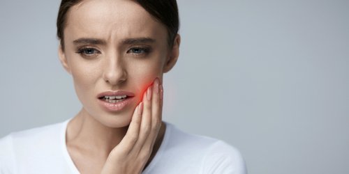 a woman feels pain due to toothache